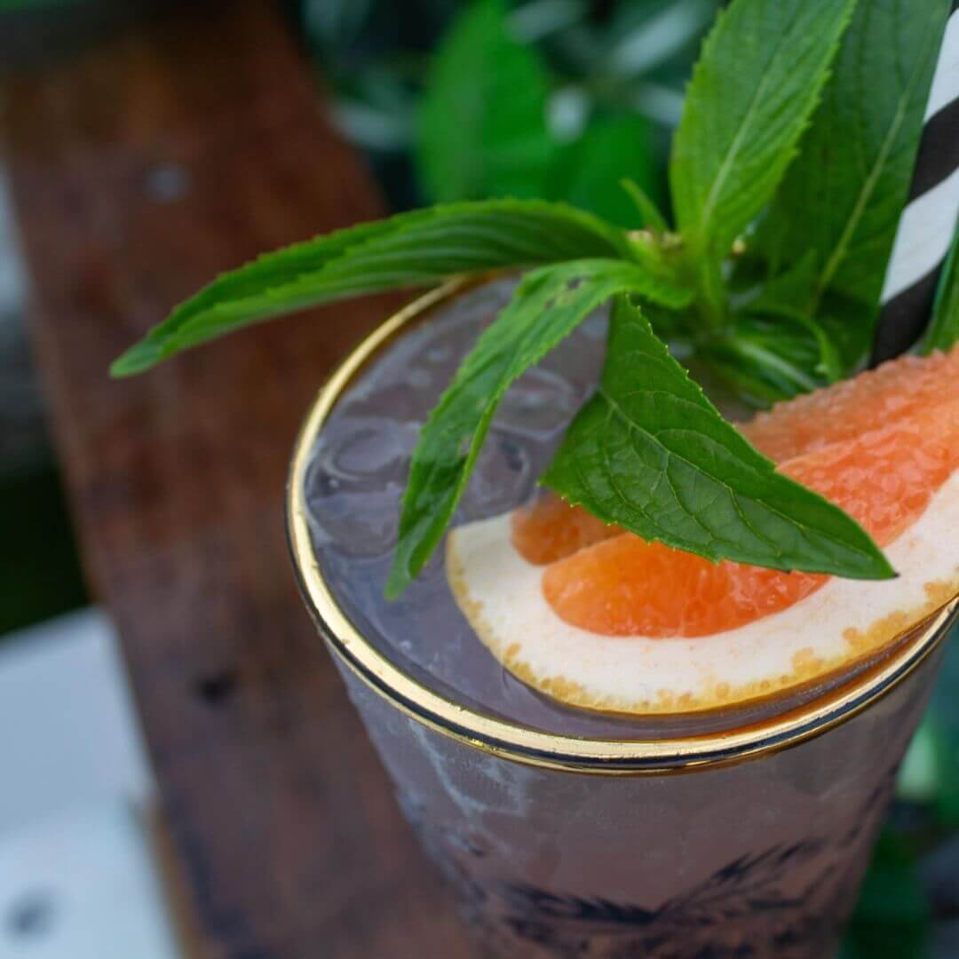 Cocktail on wooden table with slice of orange and mint leaves