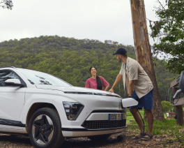 two people leaning on an ev charging car