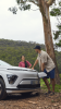 two people leaning on an ev charging car